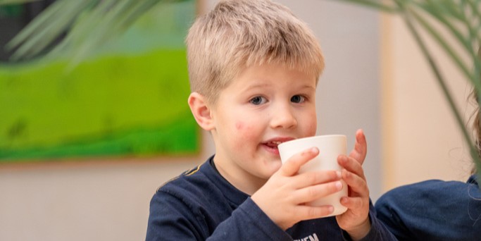 kind drinkt uit beker