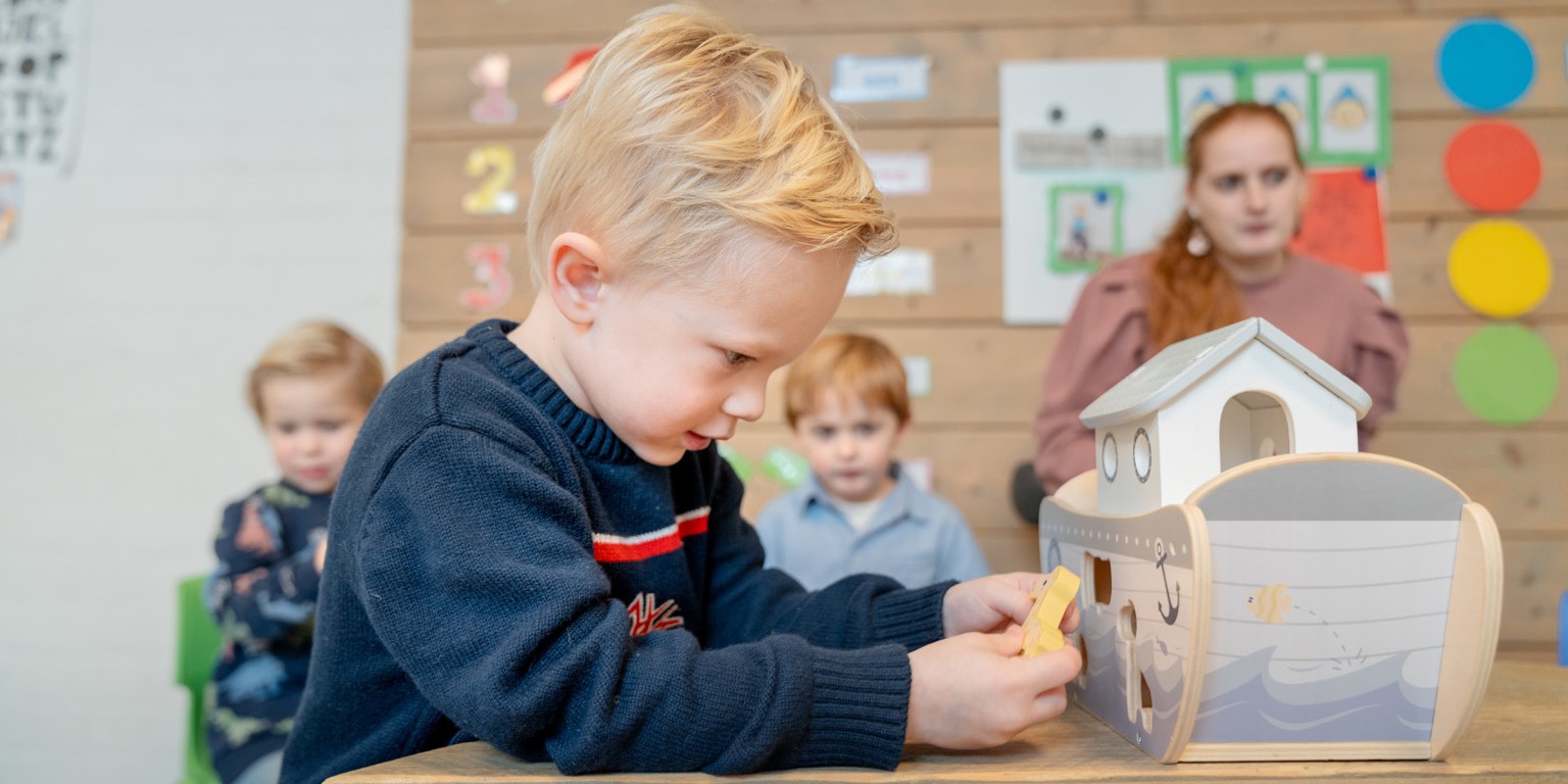 Jongen speelt met houten Ark van Noach op de groep