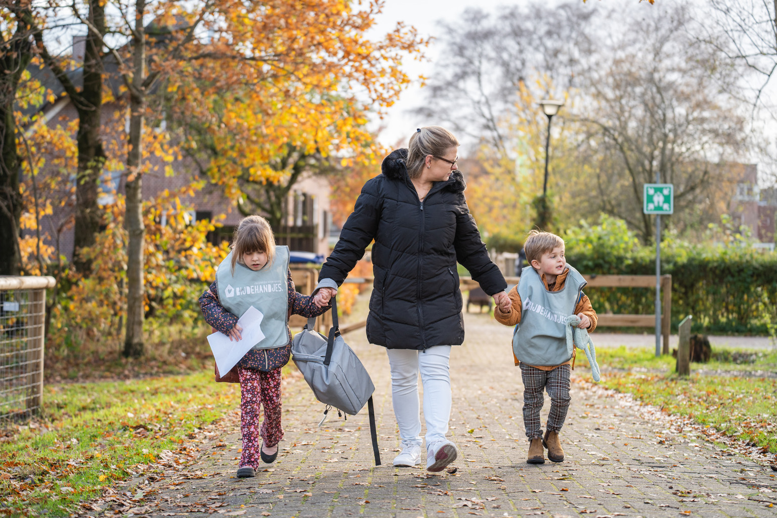 Pedagogisch medewerker loopt met kinderen naar de ingang van de BSO