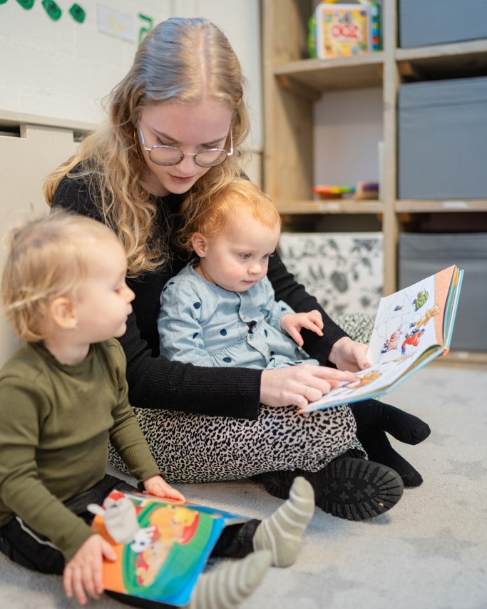Pedagogisch medewerker leest boek met kinderen