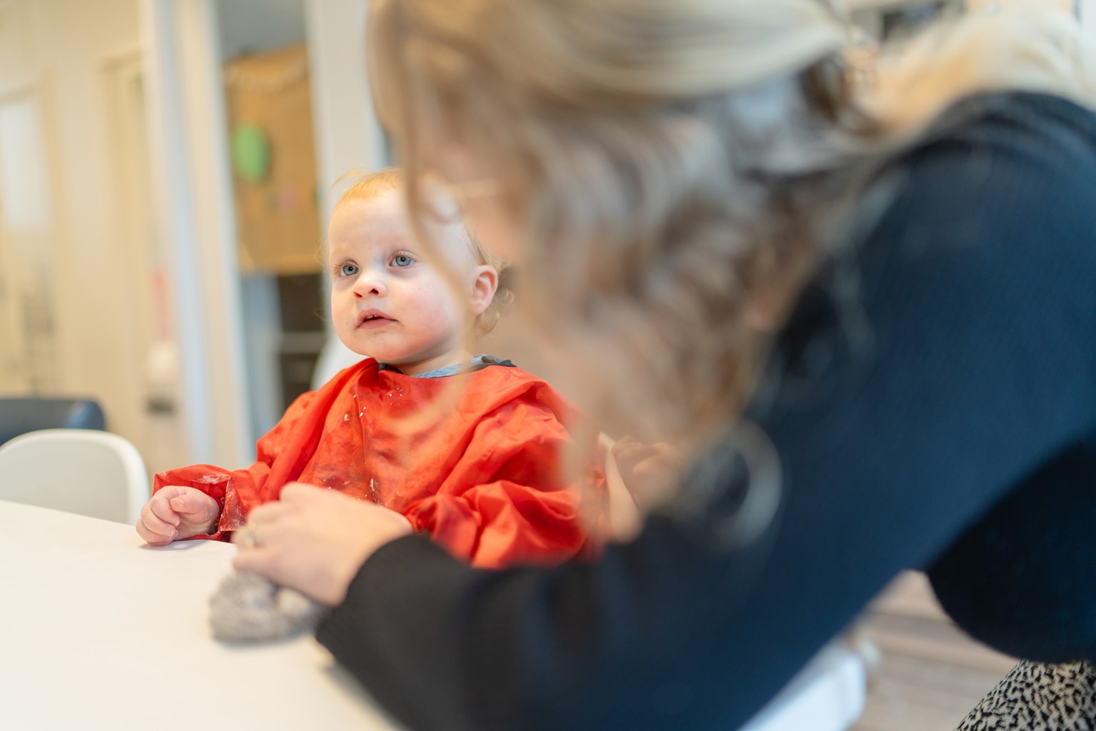 Pedagogisch medewerker zit aan tafel met kind