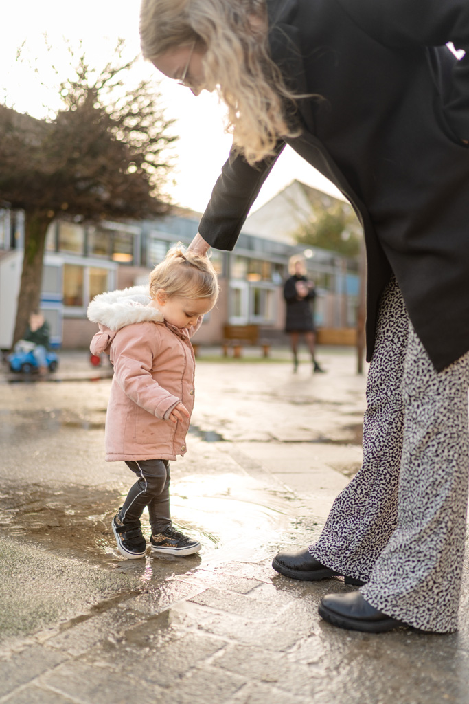 Pedagogisch medewerker steunt meisje op het buitenplein