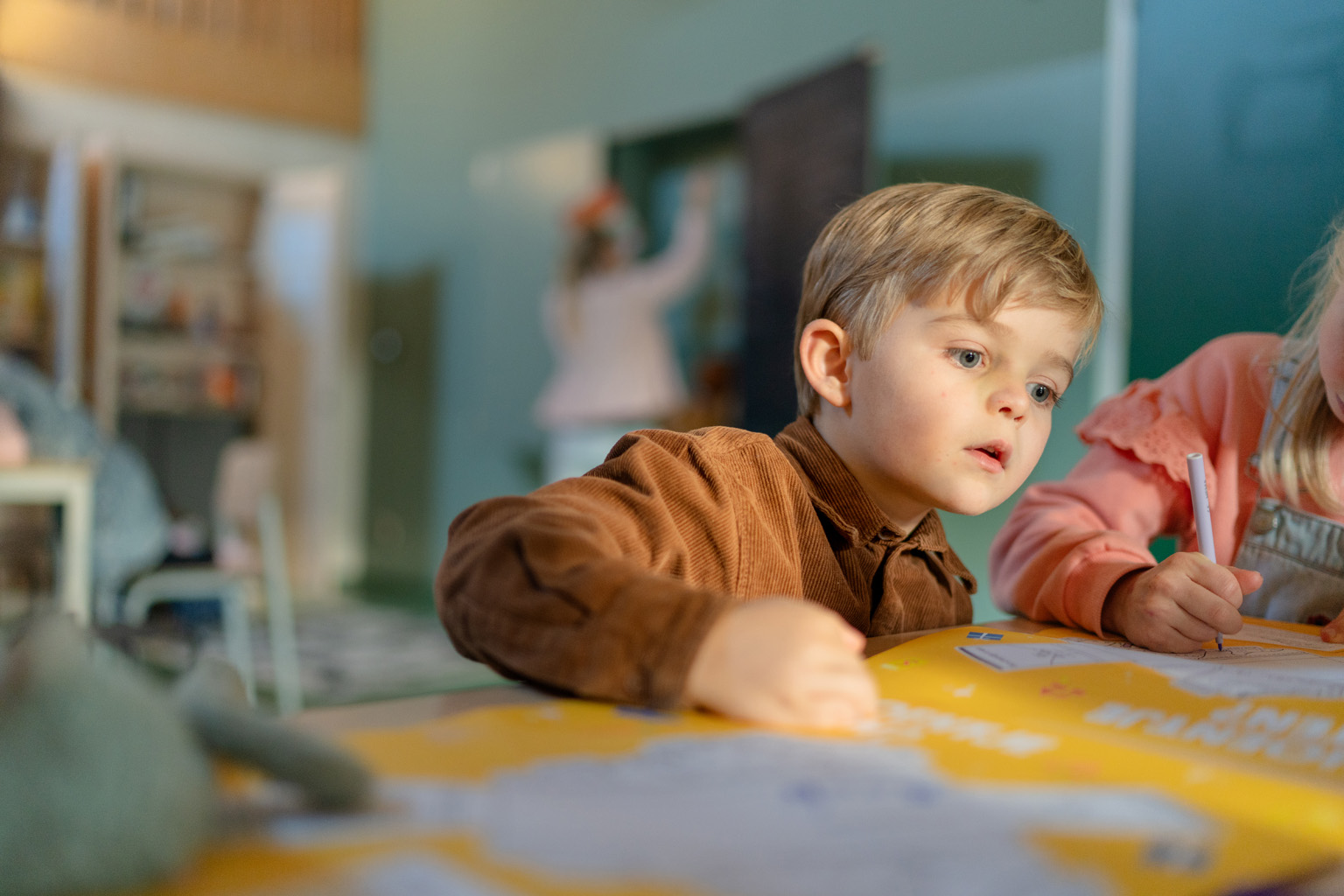 Jongen kijkt geconcentreerd naar iets op tafel