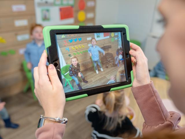 pedagogisch medewerker filmt kinderen met tablet