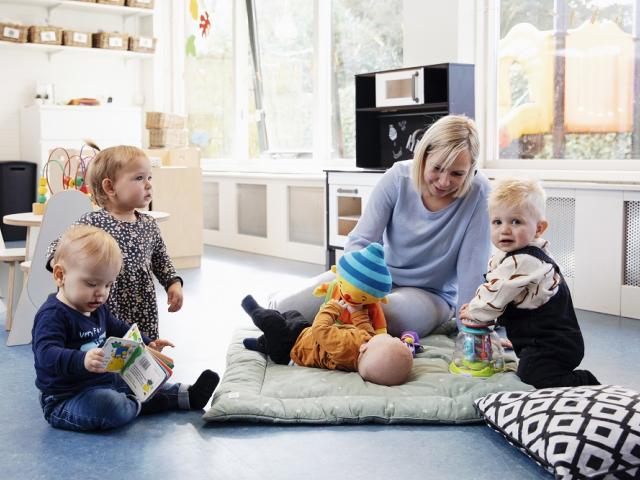 Pedagogisch medewerker en kinderen op speelkleed met Puk bij BijdeHandjes Zuiderzeestraatweg in Elburg