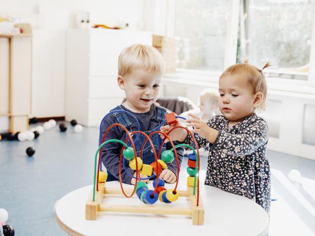 Jongen en meisje spelen met kralenboog op het kinderdagverblijf