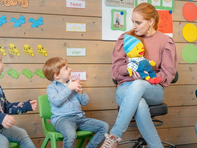 Pedagogisch medewerker in de kring met Puk op schoot