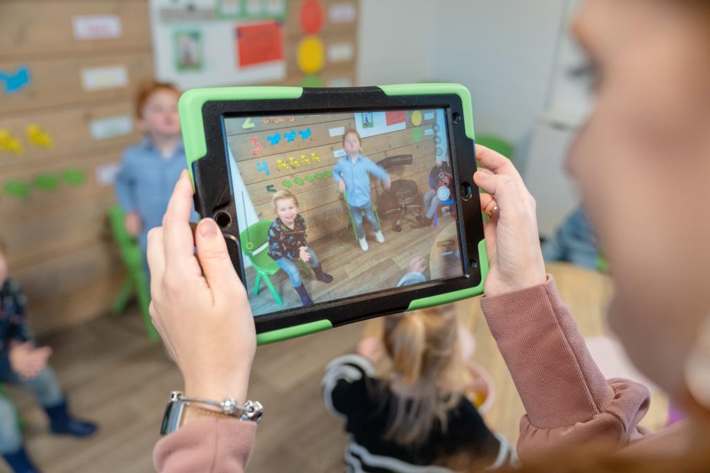pedagogisch medewerker filmt kinderen met tablet
