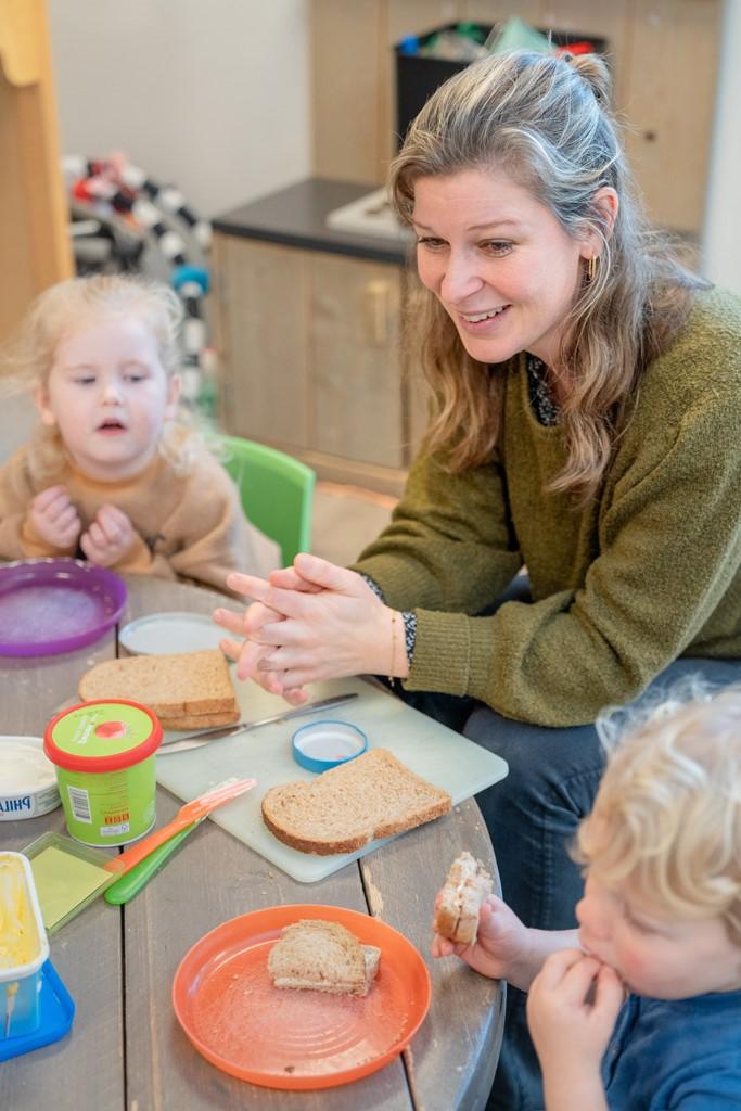Pedagogisch medewerker zit aan tafel met peuters