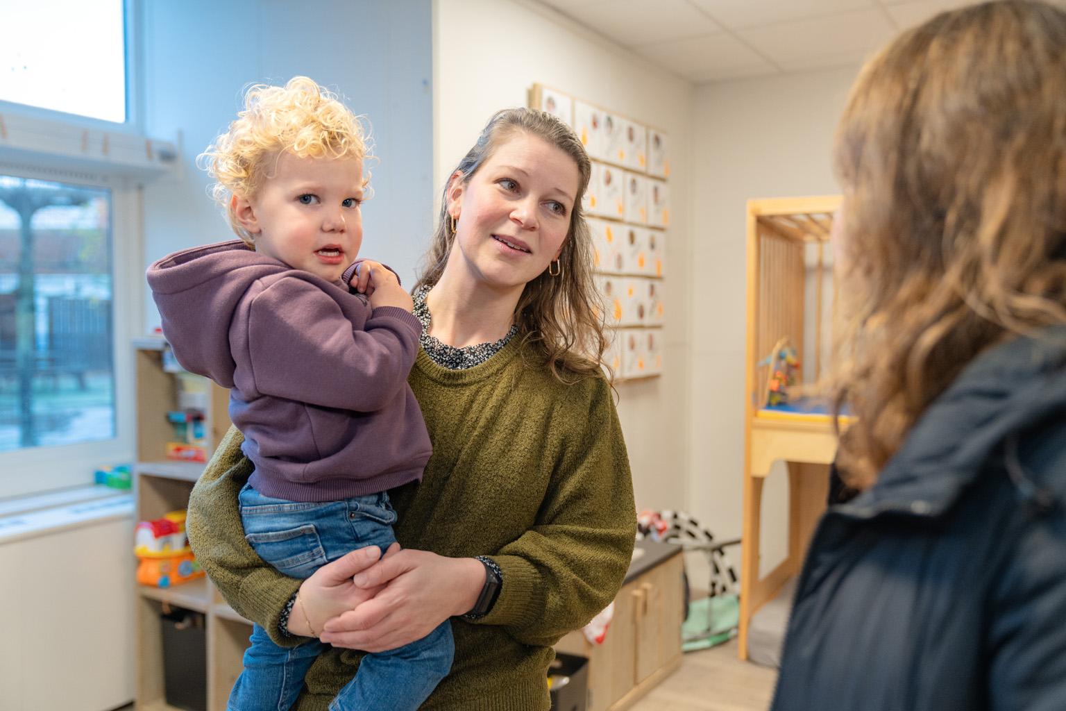 Kind wordt opgetild door moeder
