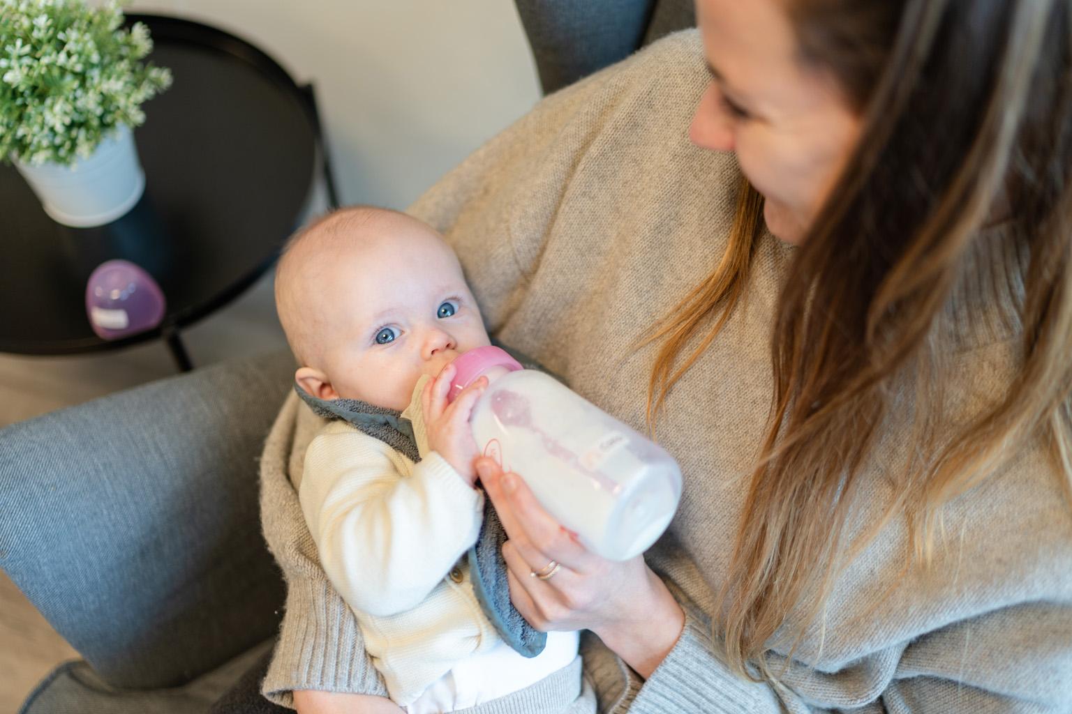 Baby drink fles op schoot bij pedagogisch professional